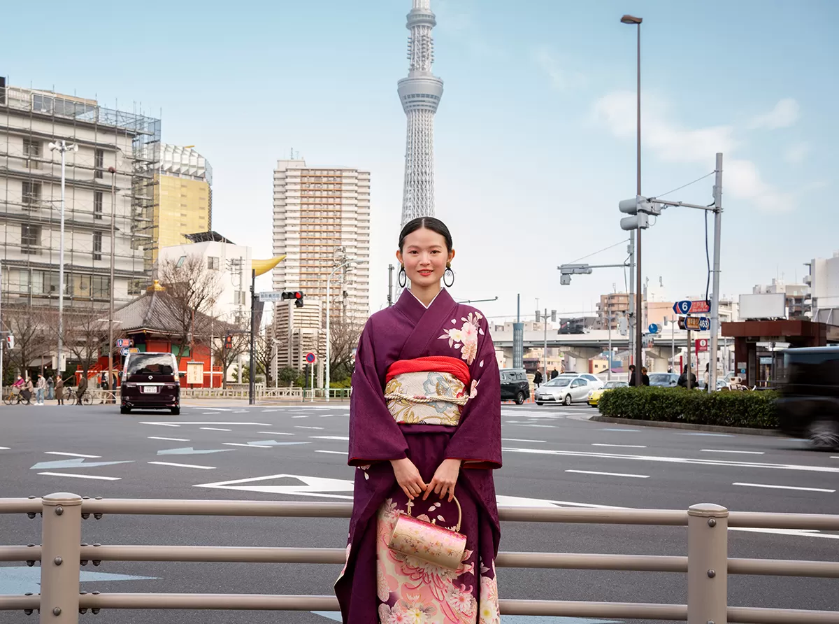 Study in Japan – Universities, Scholarships & Study Abroad Costs A Japanese student girl wearing traditional clothing, standing in a vibrant city setting.