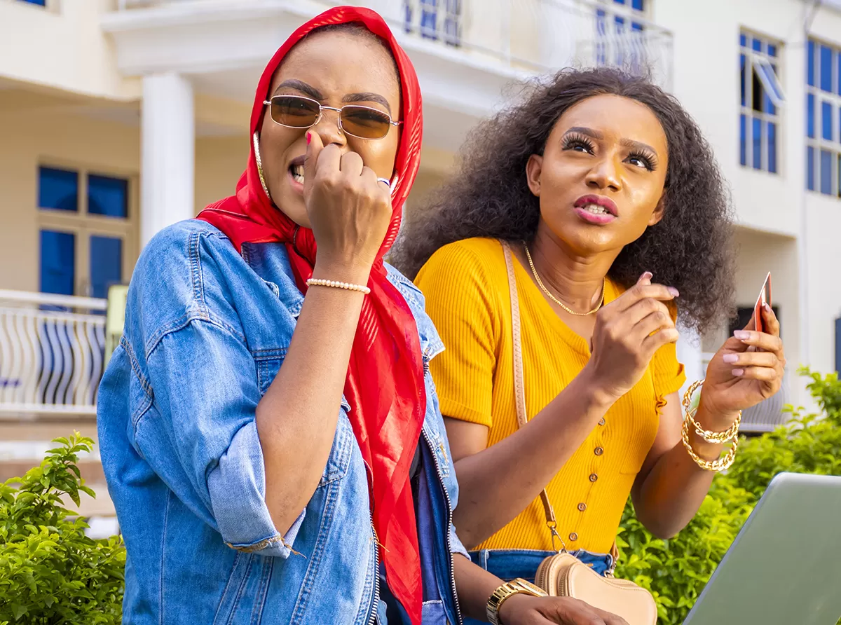 Two students studying and talking in front of a college building, embracing academic life.
