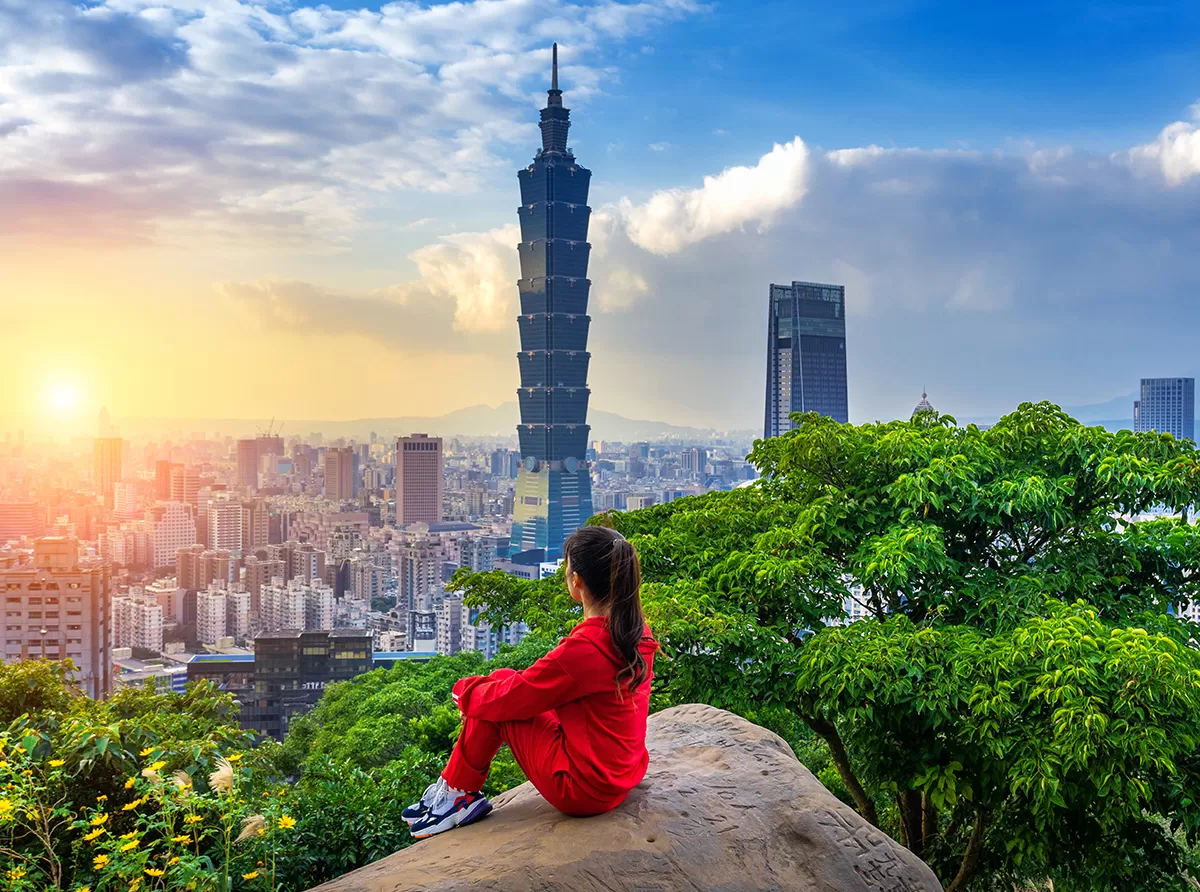 Study in Taiwan – Universities, Scholarships & Student Life A student sitting on a mountain overlooking the city, inspired by a bright academic future.