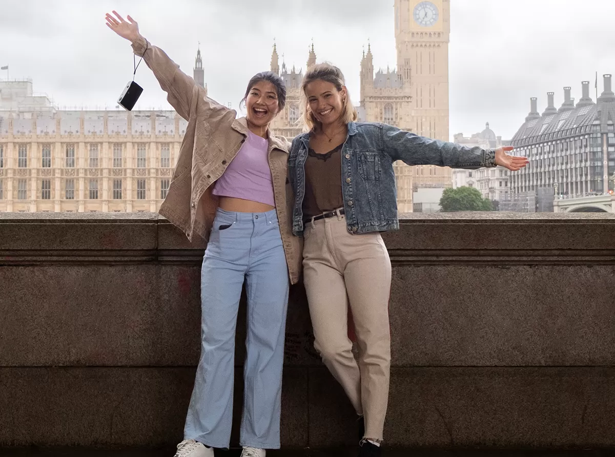 Study in the UK – Best Universities & Study Abroad Guide Two student girls standing and waving in front of Big Ben, embracing their study abroad experience.